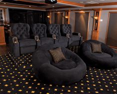 an empty theater room with black chairs and gold stars on the carpeted flooring