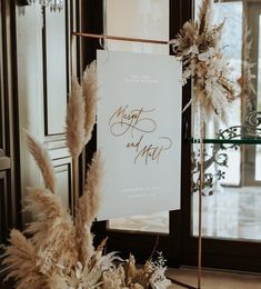 a sign that is sitting on top of a table next to some flowers and feathers