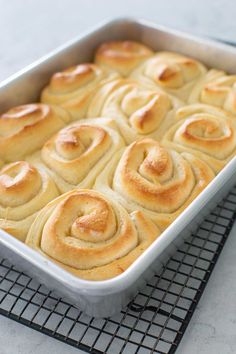 a pan filled with cinnamon rolls sitting on top of a cooling rack next to a white counter