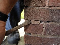 a brick wall being worked on by a man with a wrench in his hand