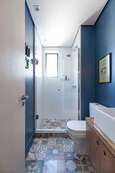 a bathroom with blue walls and tile flooring next to a white toilet in front of a walk in shower