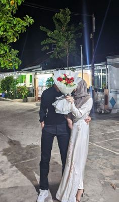 a man and woman standing next to each other in front of a building at night