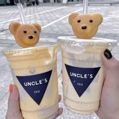 two people holding up cups with ice cream and teddy bears on the top one is iced