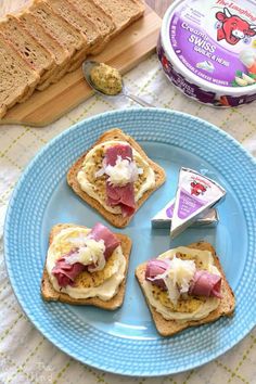 three pieces of toast with ham and cheese on them sitting on a blue plate next to a can of yogurt