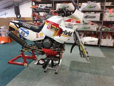 a white and red motorcycle sitting on top of a stand in a room filled with boxes