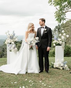 a bride and groom standing next to each other in front of an arch decorated with flowers