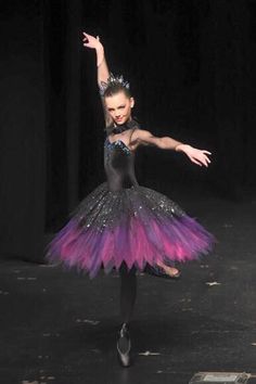 a young ballerina in a black and purple dress