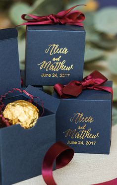 four blue boxes with gold foiled chocolates in them and ribbons tied around them