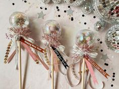 three lollipops with bows and ribbons on them are lined up in front of some disco balls