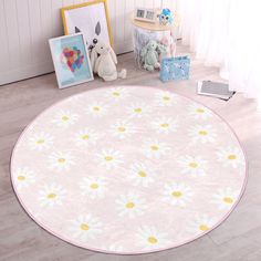 a round rug with daisies is on the floor next to pictures and stuffed animals