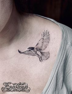 a woman's chest with a bird tattoo on it