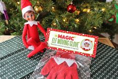 an elf is sitting in front of a christmas tree with his hands on the table