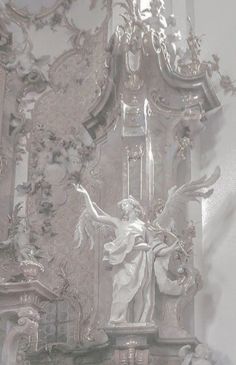 an ornate white and silver wall with angels on it