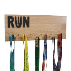 a wooden sign that says run with medals hanging from it