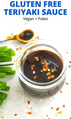 a jar filled with sauce sitting on top of a table next to some green vegetables