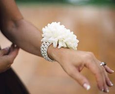 two people holding each other's hand with flowers on it and diamond bracelets