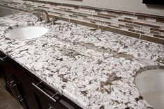 two white sinks sitting next to each other on top of a marble countertop in a bathroom