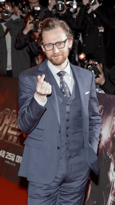 a man in a suit and tie giving the peace sign at an event with cameras around him