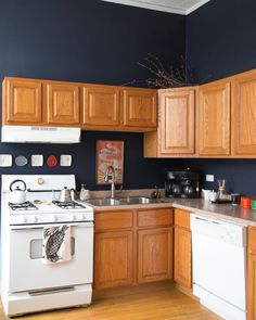 an empty kitchen with blue walls and wooden cabinets, white stove top oven and dishwasher