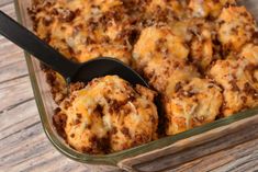 a casserole dish with cheese and meat in it on a wooden table, ready to be eaten