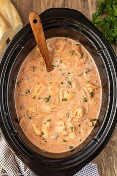 a crock pot filled with tortellini sauce and garnished with parsley