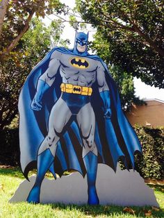 the batman statue is on display in front of some trees and bushes, with a tree behind it