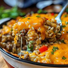 a spoon full of cheese and rice casserole being lifted from the casserole dish