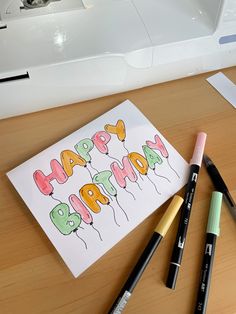 a happy birthday card sitting on top of a table next to markers and pencils