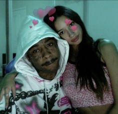 an older man and young woman posing for the camera with hearts painted on their faces