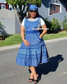 a woman standing in the street wearing a blue dress