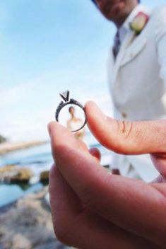 a person holding a ring with an arrow on it in front of the ocean and sky