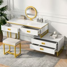 a white and gold desk with mirror, stools and potted plant in the corner