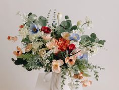 a vase filled with lots of flowers on top of a white countertop next to a wall