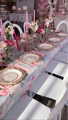 a table set with pink and white flowers, plates and candles for a formal dinner