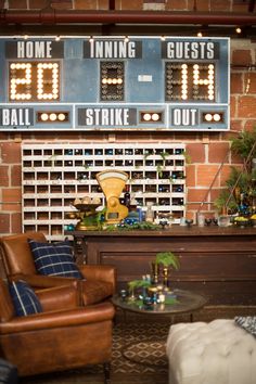 the scoreboard is hanging on the brick wall in this living room with leather chairs and a coffee table