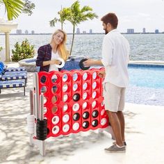 a man and woman standing next to an inflatable board game by the pool