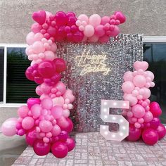 a pink balloon arch with the number fifty five on it and balloons all around it