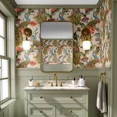 a bathroom with green walls and floral wallpaper on the vanity, along with a gold framed mirror