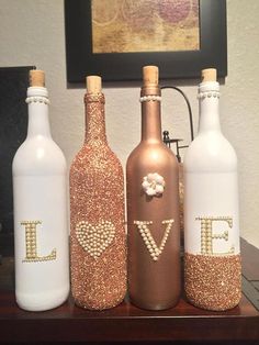 three white bottles with gold glitter letters and bows on the top, one is empty