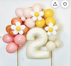 the number two is made out of balloons with flowers on them, and sits in front of a white wall