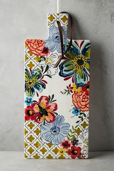 a bag with flowers on it hanging from a hook in front of a gray wall