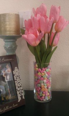 a vase filled with pink flowers sitting on top of a table next to a photo frame