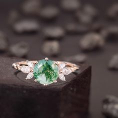 a close up of a ring with a green stone in the middle and white diamonds around it