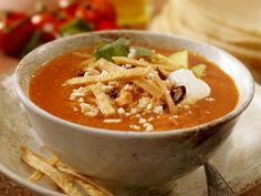 a white bowl filled with soup on top of a plate next to some crackers