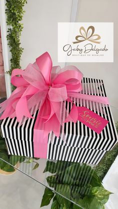 a black and white gift box with pink ribbon on it sitting on top of a table