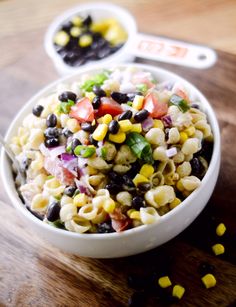 a white bowl filled with pasta salad on top of a wooden table