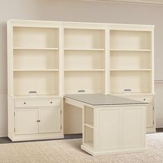 an empty room with two white bookcases and a desk in the middle is shown