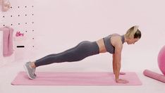 a woman is doing push ups on a pink exercise mat with a ball in the background