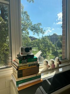 a stack of books sitting on top of a window sill next to a camera