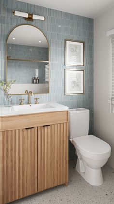 a white toilet sitting next to a wooden cabinet in a bathroom under a large mirror